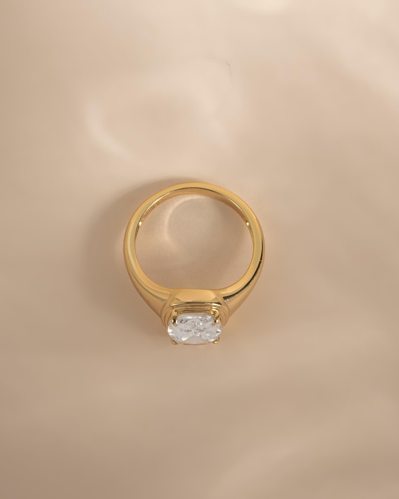 Top-down view of an elongated diamond ring in gold, styled as an engagement ring
