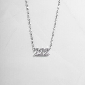 flatlay of silver 222 angel number diamond-studded necklace, minimalist design, perfect for everyday wear.
