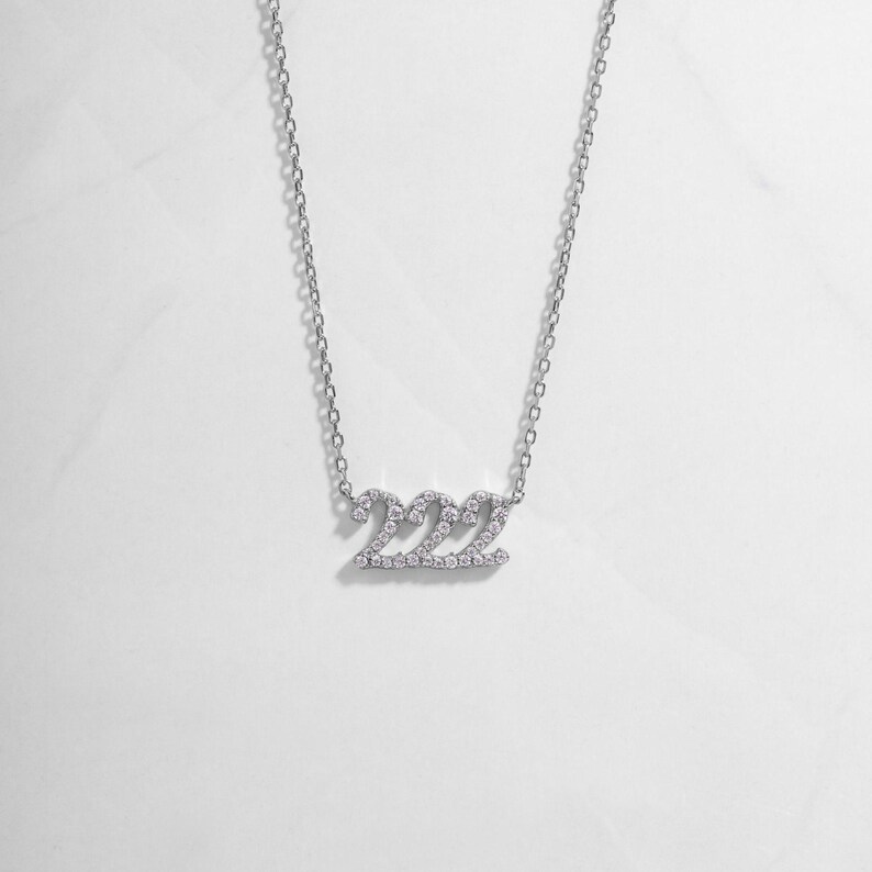 flatlay of silver 222 angel number diamond-studded necklace, minimalist design, perfect for everyday wear.