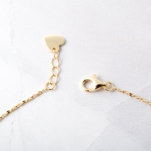 May include: A gold chain necklace with a heart-shaped clasp and a lobster claw clasp.