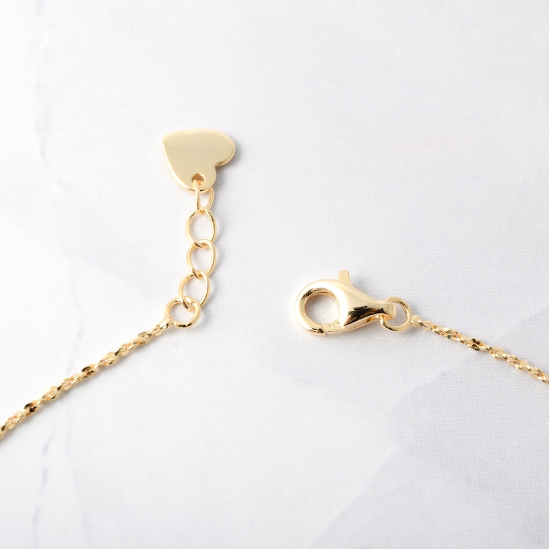 May include: A gold chain necklace with a heart-shaped clasp and a lobster claw clasp.