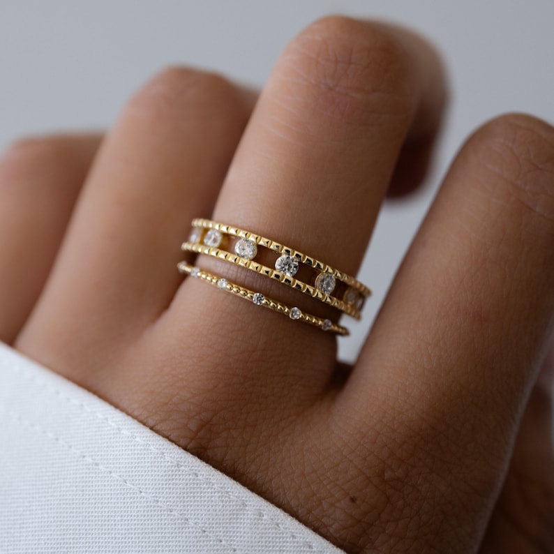 Model wearing gold statement ring paired with a delicate stacking ring