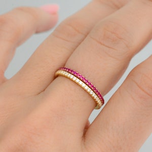Puede incluir: Dos anillos de oro con una fila de peque&ntilde;as piedras preciosas rosas y una fila de peque&ntilde;as piedras preciosas blancas.