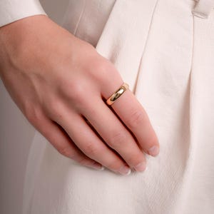 a model showcasing a simple gold ring for women