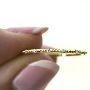 Model holding dainty gold ring with diamonds
