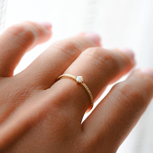 model wearing thin ring featuring cubic zirconia stones and opal birthstone