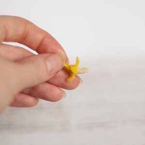 Puede incluir: Un pequeño plátano de fieltro con piel amarilla y tallo blanco.