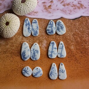 Può includere: Sei paia di orecchini in ceramica a forma di lacrima con un motivo craquelé blu e bianco.