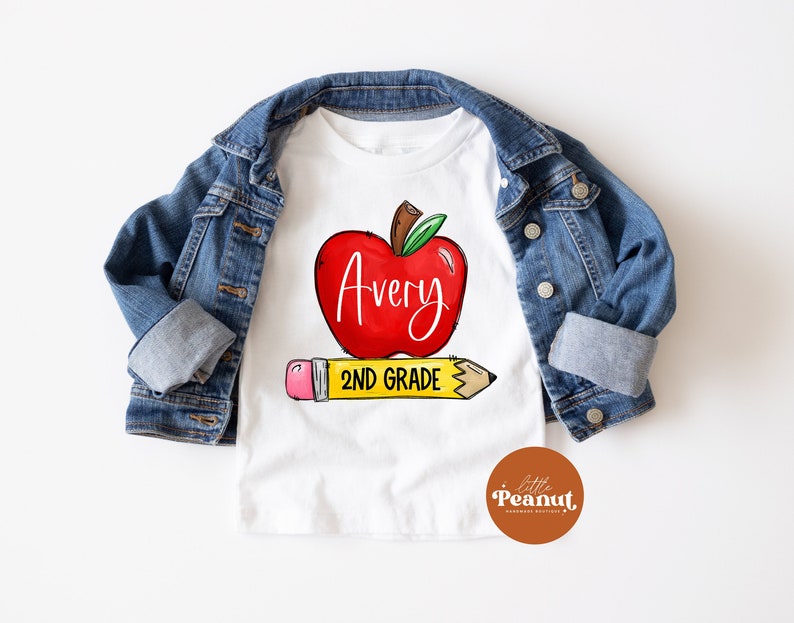 May include: White t-shirt with a red apple graphic and the text "Avery 2nd Grade" on a yellow pencil.