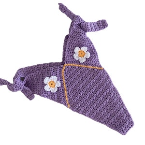 Puede incluir: Top de crochet lavanda hecho a mano con detalles de margaritas. El top de cuello halter tiene cierres de lazo y está adornado con dos apliques de margaritas blancas y amarillas. La puntada de crochet crea una apariencia texturizada.