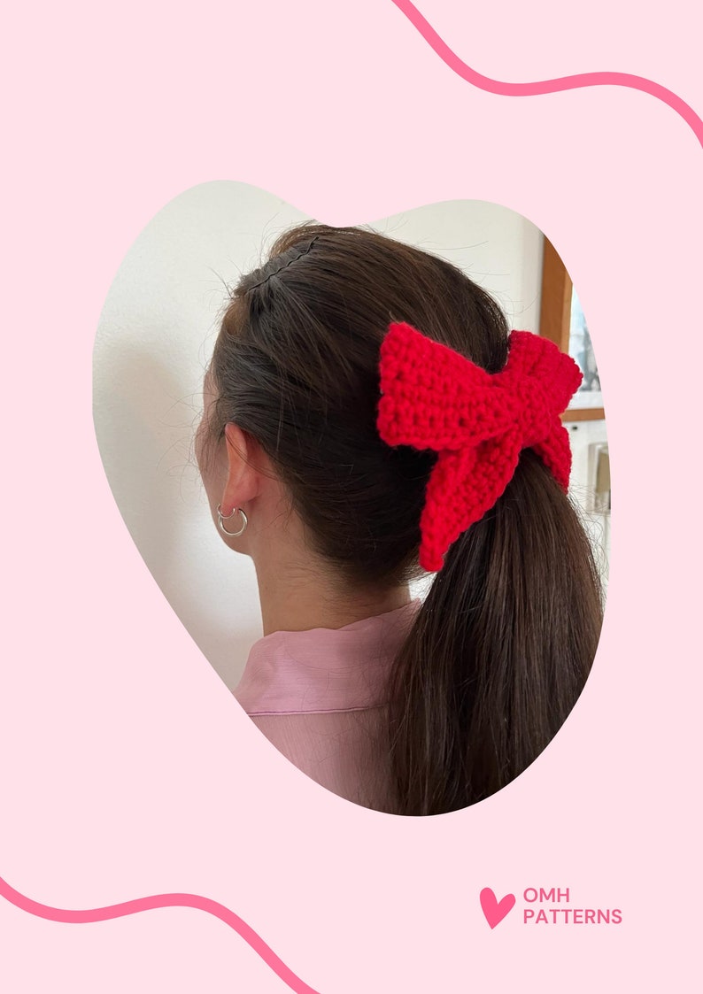 May include: A red crocheted bow hair tie. The bow is tied around a ponytail.