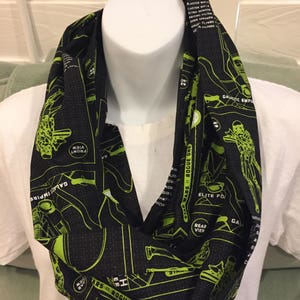 May include: A black and green infinity scarf with a Star Wars: Rogue One schematic design. The design includes the text "Star Wars: Rogue One" and "Galactic Empire".