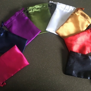 May include: Assortment of eight small satin drawstring bags in various colours, including black, red, pink, purple, green, gold, and white.
