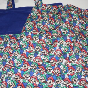 May include: A blue and white reusable tote bag featuring a pattern of Mario and Luigi characters. The bag has two handles and a blue lining.