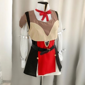Op de afbeelding: Een cosplay-kostuum op een mannequin. De outfit heeft een wit gestreept overhemd, een beige en bruin vest, een zwarte en rode rok en een zwarte riem. Het kostuum heeft zilveren accenten en een rode strik.