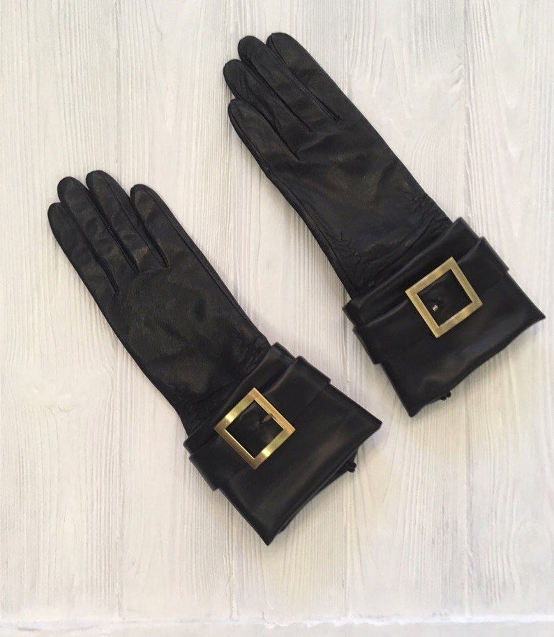 May include: A pair of black leather gloves with gold buckles on the cuffs.