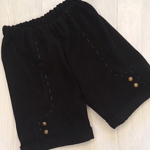 May include: Black shorts with a cuffed hem and decorative stitching. The shorts have three gold buttons on each side.