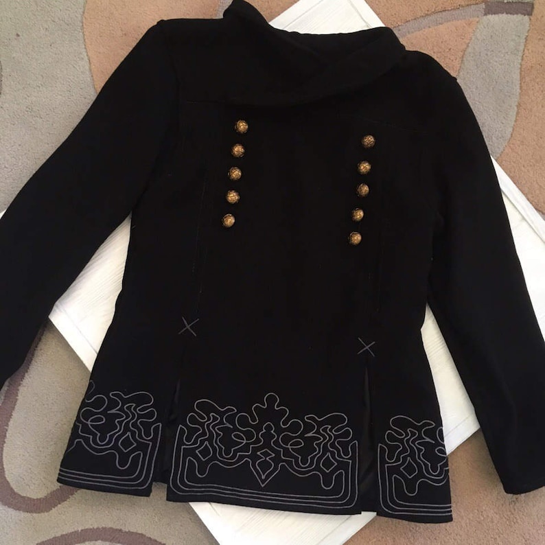 May include: A black blazer with gold buttons and a decorative embroidered trim. The blazer has a high collar and long sleeves.