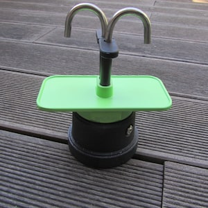 May include: A green and black stovetop espresso maker with a drip tray and two spouts.