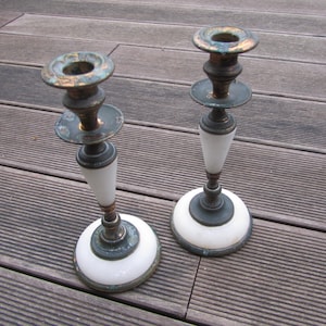 Può includere: Un paio di candelabri antichi in ottone con basi in marmo bianco. I candelabri hanno una finitura anticata e sono in buone condizioni.