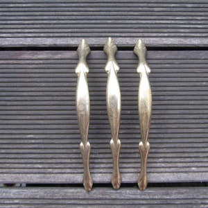 Peut inclure: Trois poignées de porte de placard en métal doré avec un design décoratif et orné.