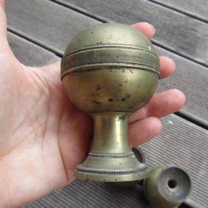 Op de afbeelding: Een messing deurknop met een ronde bovenkant en een decoratieve band. De knop is versleten en heeft een patina-afwerking.