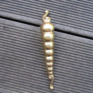 Puede incluir: Una manija de puerta de metal de color dorado con un diseño decorativo y bulboso.