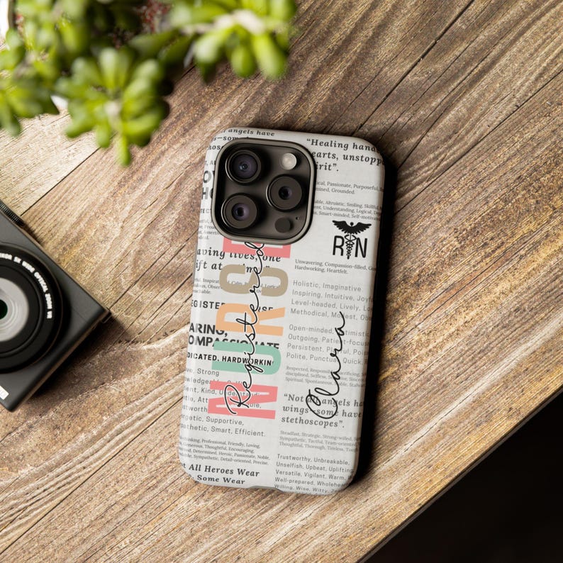 May include: A white iPhone case with a newspaper-style design featuring the words "Registered Nurse" and "RN" in a black and white logo. The case has a black camera bump with three lenses.