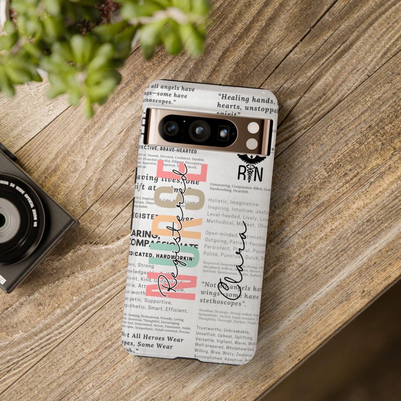 May include: A white phone case with a colorful design featuring the words "Registered Nurse" and a variety of positive adjectives. The case also includes the text "Not all heroes wear wings, some have stethoscopes."