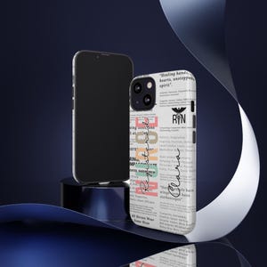 May include: A white iPhone case with a colorful design featuring the word "Registered Nurse" and a list of positive adjectives describing the profession. The case also includes the text "Healing hands, hearts, unstoppable spirit" and "Not all angels have wings, some have stethoscopes".