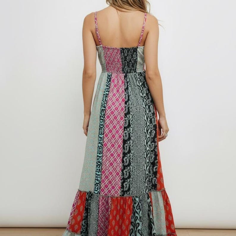 K&ouml;nnte beinhalten: Ein langes, gemustertes Kleid mit Spaghettitr&auml;gern. Das Kleid hat ein Patchwork-Design mit verschiedenen Mustern und Farben, darunter Rosa, T&uuml;rkis, Schwarz und Rot. Das Oberteil ist eng anliegend und der Rock f&auml;llt mit einem R&uuml;schensaum bis zum Boden.