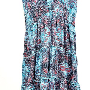 May include: A sleeveless dress with a V-neckline and a tiered skirt. The dress features a paisley pattern in shades of blue, red, and black. The fabric appears lightweight and flowing, suitable for warm weather.