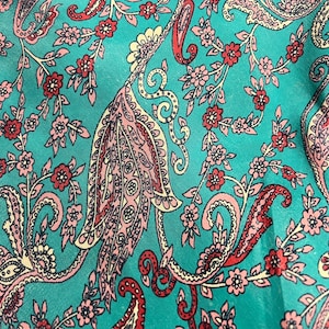 May include: Teal fabric with a paisley pattern in pink, red, and cream. The pattern features intricate swirls and floral motifs.