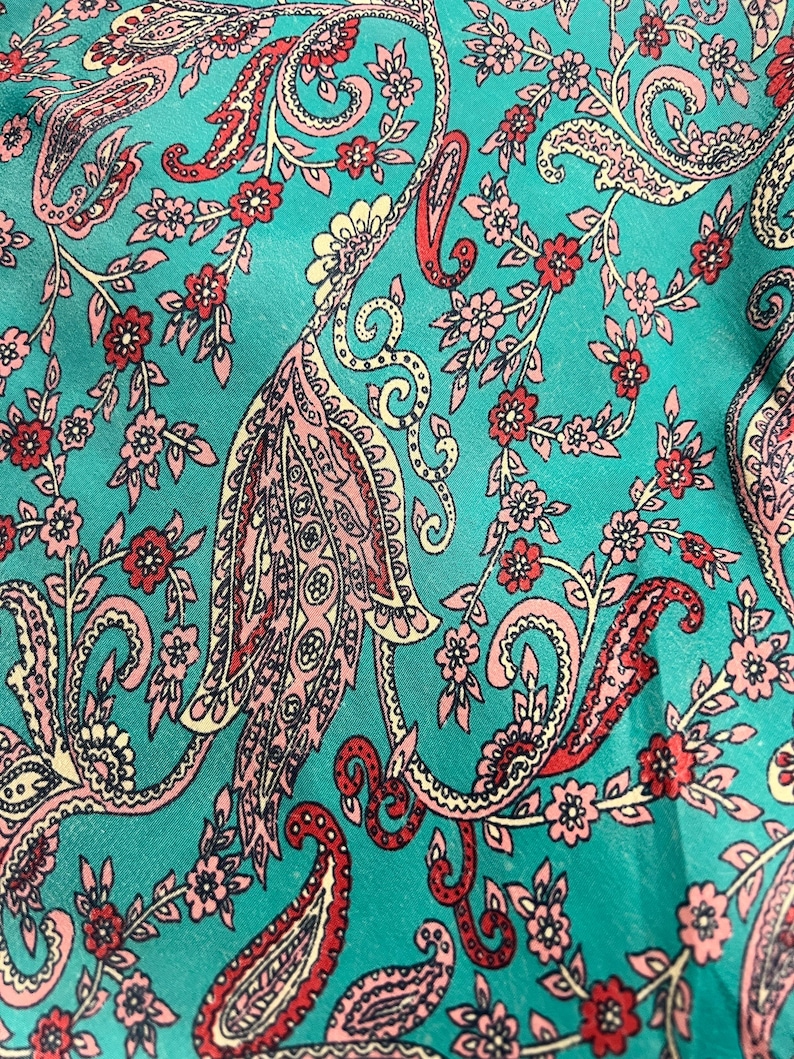 May include: Teal fabric with a paisley pattern in pink, red, and cream. The pattern features intricate swirls and floral motifs.