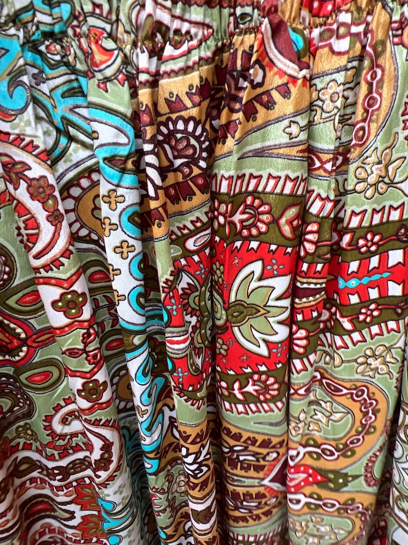 May include: Close-up of a fabric with a paisley pattern in shades of green, red, brown, and white.