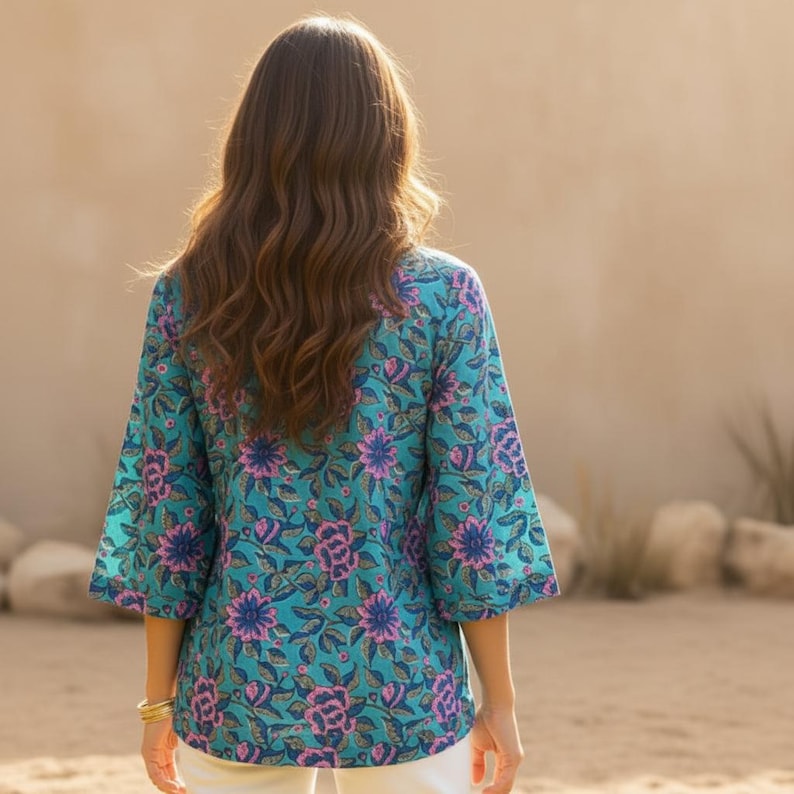May include: A turquoise floral print top with three-quarter sleeves. The top features a vibrant pattern of pink and blue flowers and green leaves. The garment is made of a lightweight fabric, perfect for warm weather.