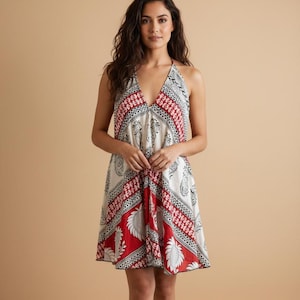 Puede incluir: Vestido halter con escote en V. El vestido presenta un estampado de cachemira rojo, blanco y negro. La parte de la falda tiene un borde rojo con un diseño de hojas blancas. El vestido llega a la rodilla.
