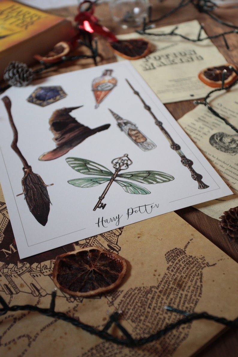 Op de afbeelding: Een wit vel papier met een Harry Potter-thema. Het papier heeft illustraties van een bezem, een hoed, een sleutel met libellenvleugels, een fles, een toverstaf en een personage. De tekst "Harry Potter" staat in cursief onderaan de pagina.