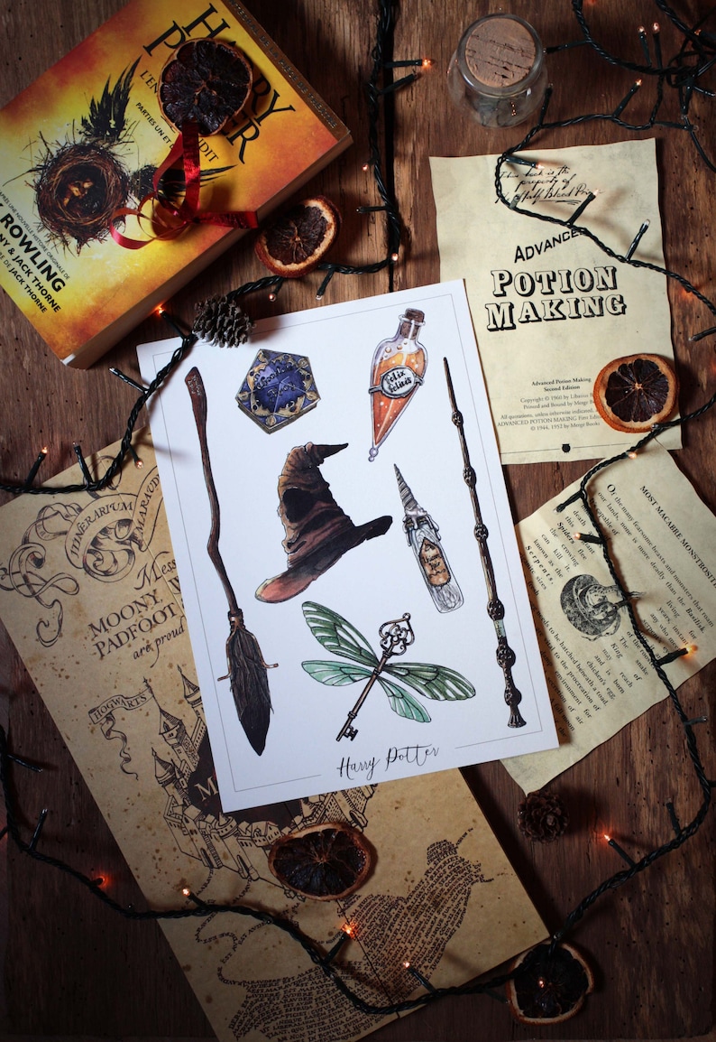 Op de afbeelding: Een witte print met aquarel illustraties van Harry Potter-thema objecten, waaronder een bezem, een sorteerhoed, een toverstaf, een sleutel, een fles Felix Felicis en een gouden snitch. De print is getiteld "Harry Potter".