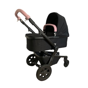 May include: A black stroller with a pink leather handle and a black fabric canopy. The stroller has a black basket underneath and four black wheels.