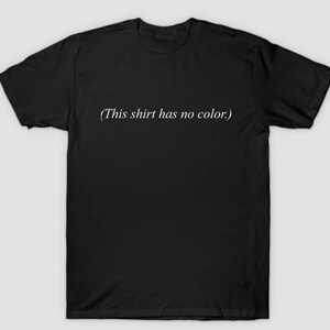 Może przedstawiać: Czarny t-shirt z nadrukiem "(This shirt has no color.)" w kolorze białym na przodzie.