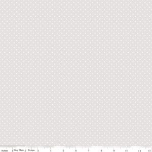 May include: A light gray fabric with a repeating pattern of small white polka dots. The fabric is measured in inches, with a ruler along the bottom edge. The text "Riley Blake Designs" is visible.