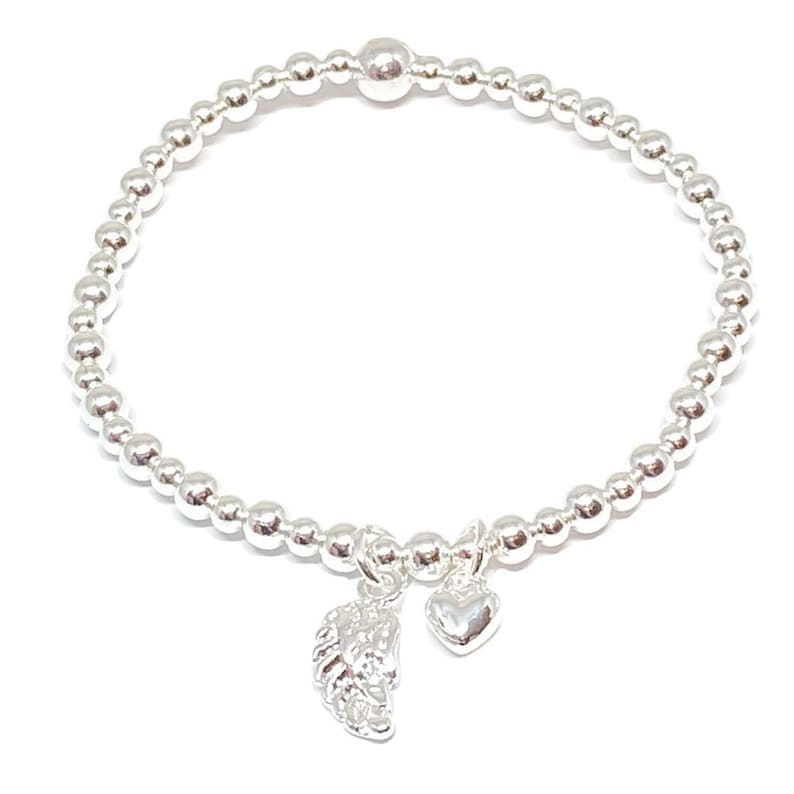 Puede incluir: Un brazalete de cuentas de plata con un dije de coraz&oacute;n y un ala.