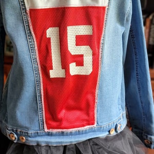 May include: A blue denim jacket with a red and white patch on the back. The patch says "Crimson Tide" and has the number "15" on it.