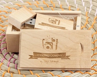 Könnte beinhalten: Ein heller USB-Stick aus Holz mit einer passenden Schiebebox aus Holz. Der Stick und der Deckel der Box sind mit einem Kamerasymbol, dem Text "EDEN PHOTOGRAPHY" und einer handschriftlichen Signatur graviert. Die Holzmaserung ist sichtbar.