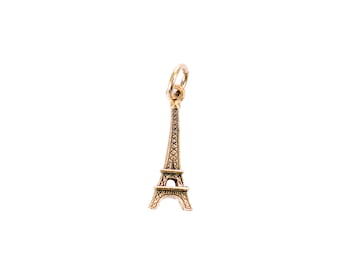 May include: A gold-colored Eiffel Tower charm with a loop at the top for attaching to a necklace or bracelet.