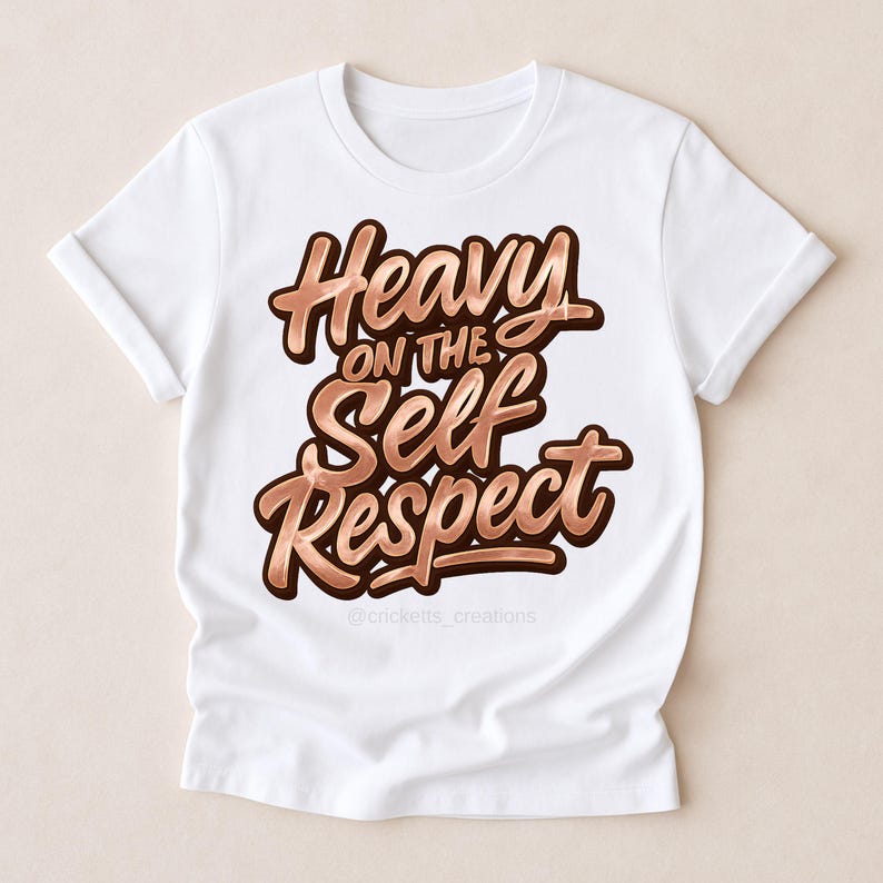 Puede incluir: Camiseta blanca con la frase "Heavy on the Self Respect" en fuente marr&oacute;n con efecto met&aacute;lico y sombra. La camiseta tiene las mangas enrolladas. El @cricketts_creations est&aacute; en la parte inferior.