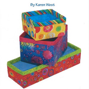 Puede incluir: Un conjunto de tres cajas de tela coloridas con una variedad de patrones, incluyendo círculos, rayas y remolinos. Las cajas están apiladas una encima de la otra y están etiquetadas como "Fusible Fabric Boxes" y "By Karen West". La imagen también incluye el texto "#FLF115" y "For the Love of Fabric" con la dirección del sitio web "www.lovethefabric.com".