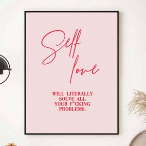 May include: A framed pink print with the words "Self love" in red script, followed by the text "Will literally solve all your f*cking problems." The print is displayed on a white wall above a wooden cabinet.