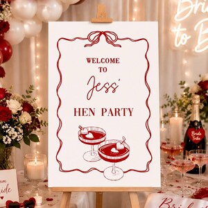 Puede incluir: Un letrero que dice "Welcome to Jessi Hen Party" se muestra en un caballete, con un borde rojo e ilustraciones de c&oacute;cteles. La escena incluye globos, flores, velas y una banda de "Bride to Be".